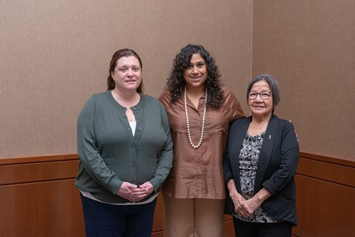Three Soonats’ooneh Health Society team members standing together and smiling in a meeting room.
