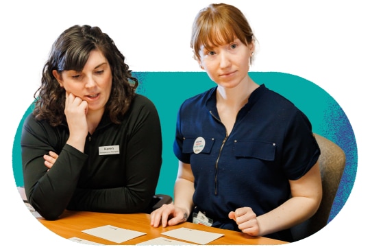 Two healthcare workers look at cards on a table