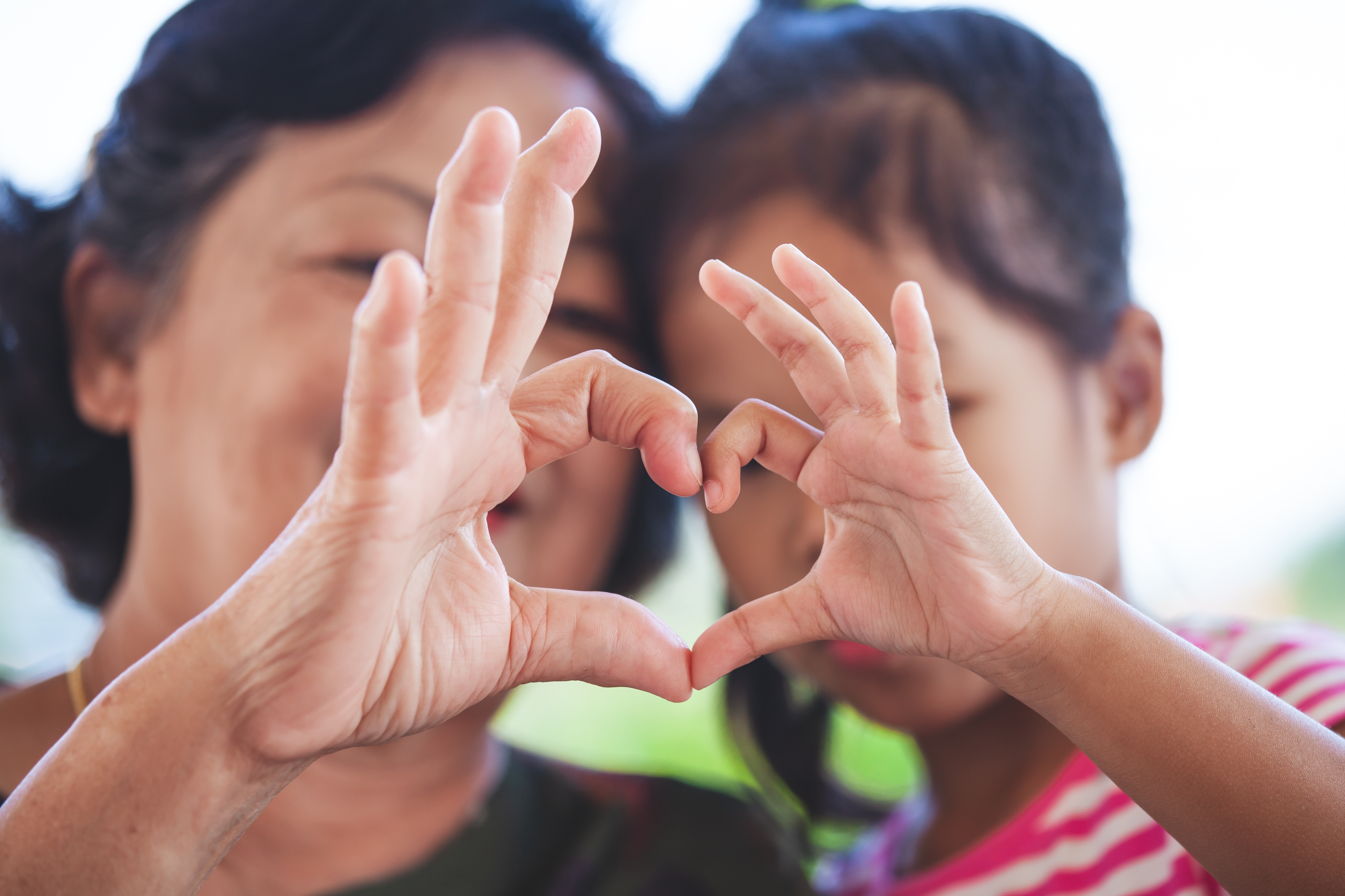 Un enfant et un adulte joignent leurs mains pour former un cœur.