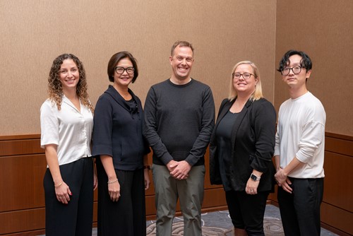 Five team members from the Victorian Order of Nurses for Canada standing together and smiling in a meeting room.