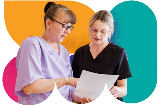 Two healthcare workers look at a document together.